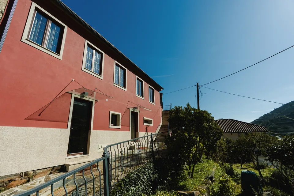 Angled facade with path railing, planting and hillside to the right